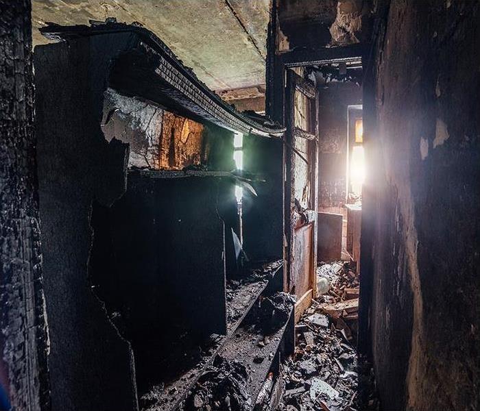 room in house with burned furniture and charred walls in black soot.